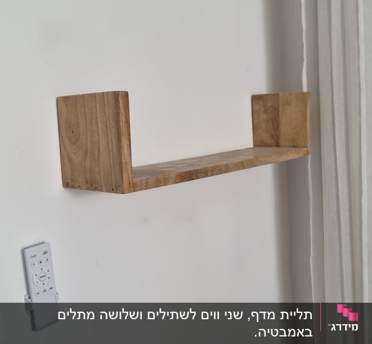 מדף עץ מותקן על קיר לבן עם שלט רחוק